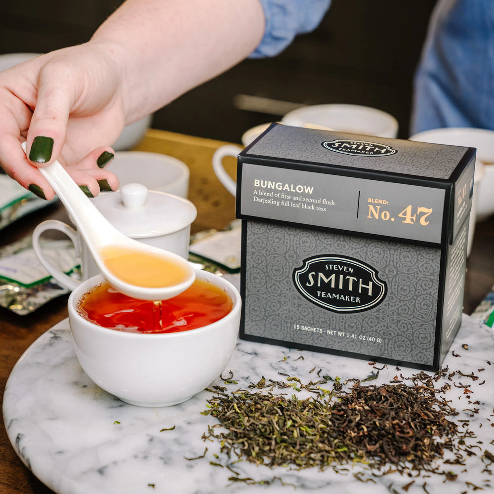 Black box of Bungalow tea with Smith logo next to a brewed cup of tea and loose blend.