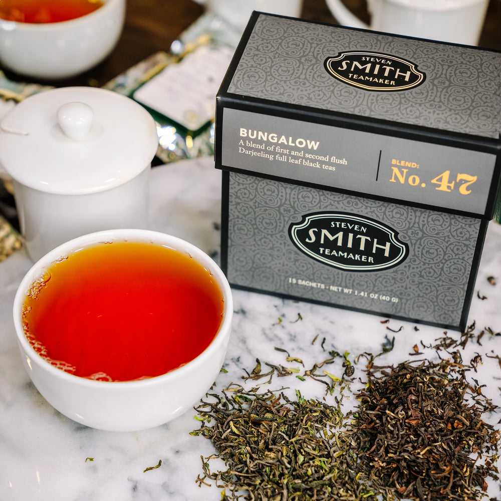 Black box of Bungalow tea with Smith logo next to a brewed cup of tea and loose blend.