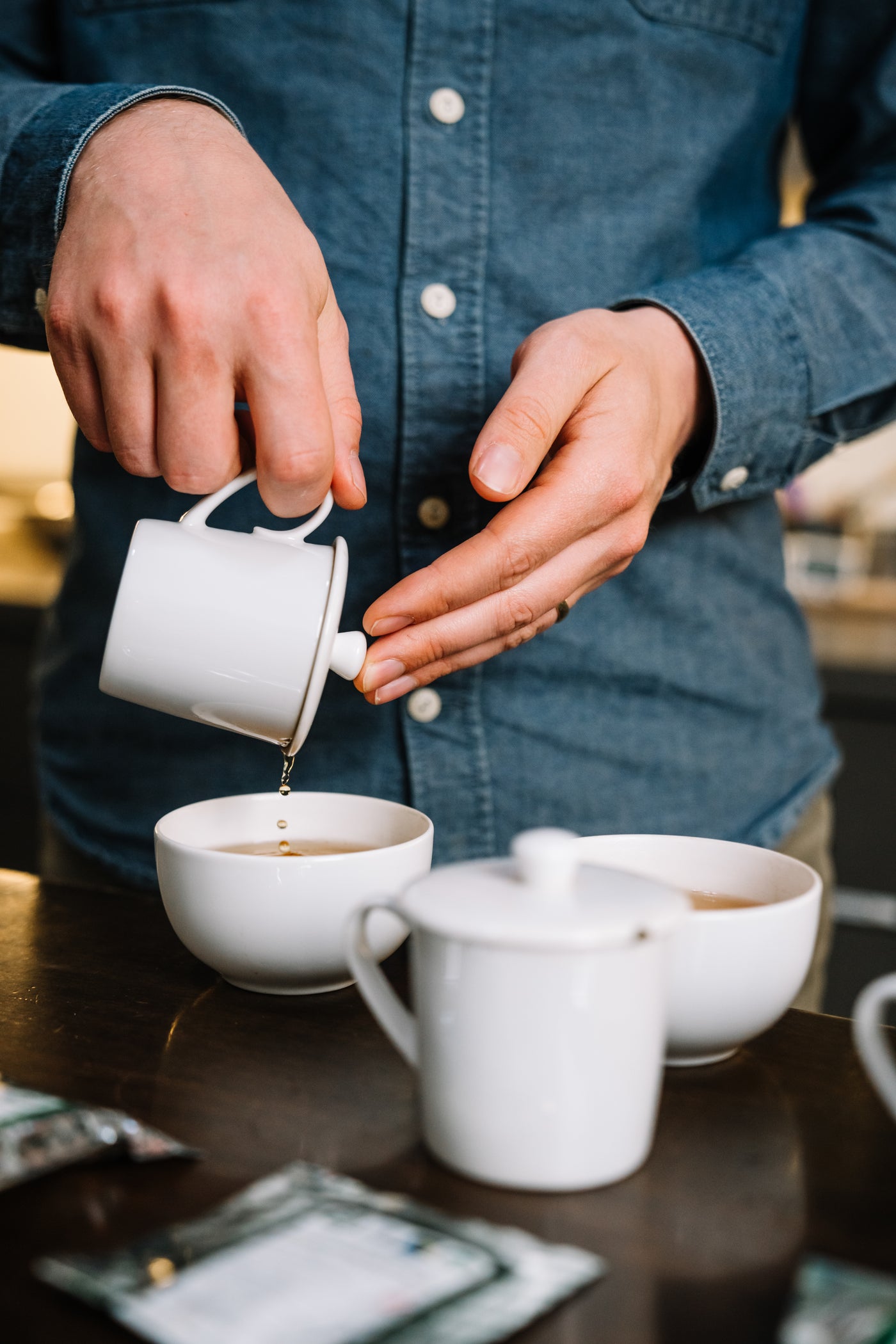 Donovan Eilert, teamaker, straining a cup of Darjeeling tea on a table crowded with sample cups.