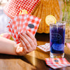 Deck of Smith Teamaker playing cards with red and white gingham pattern and Smith Teamaker logo fanned out next to a glass of iced tea.