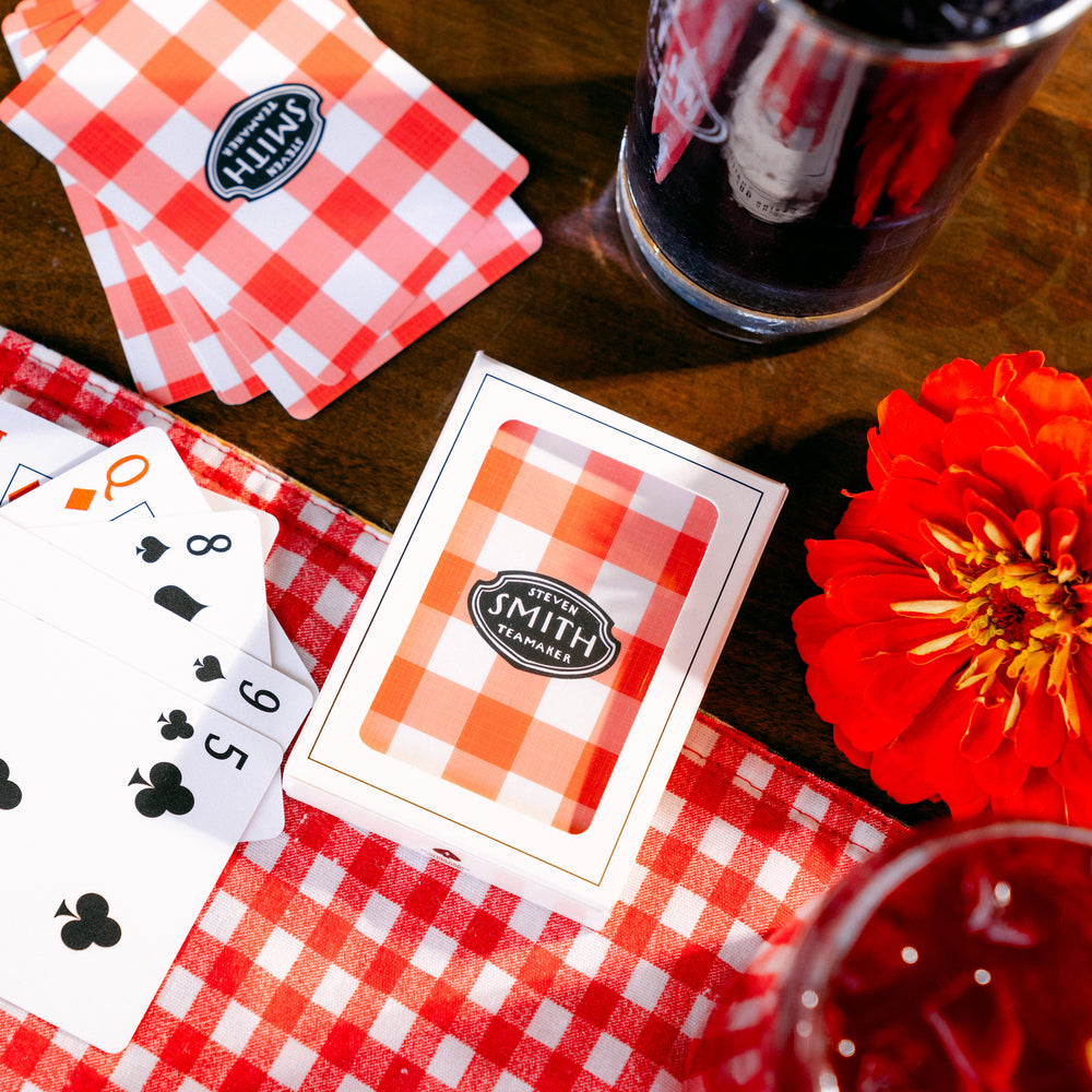 Zoomed out view of deck of Smith Teamaker playing cards with red and white gingham pattern and Smith Teamaker logo.