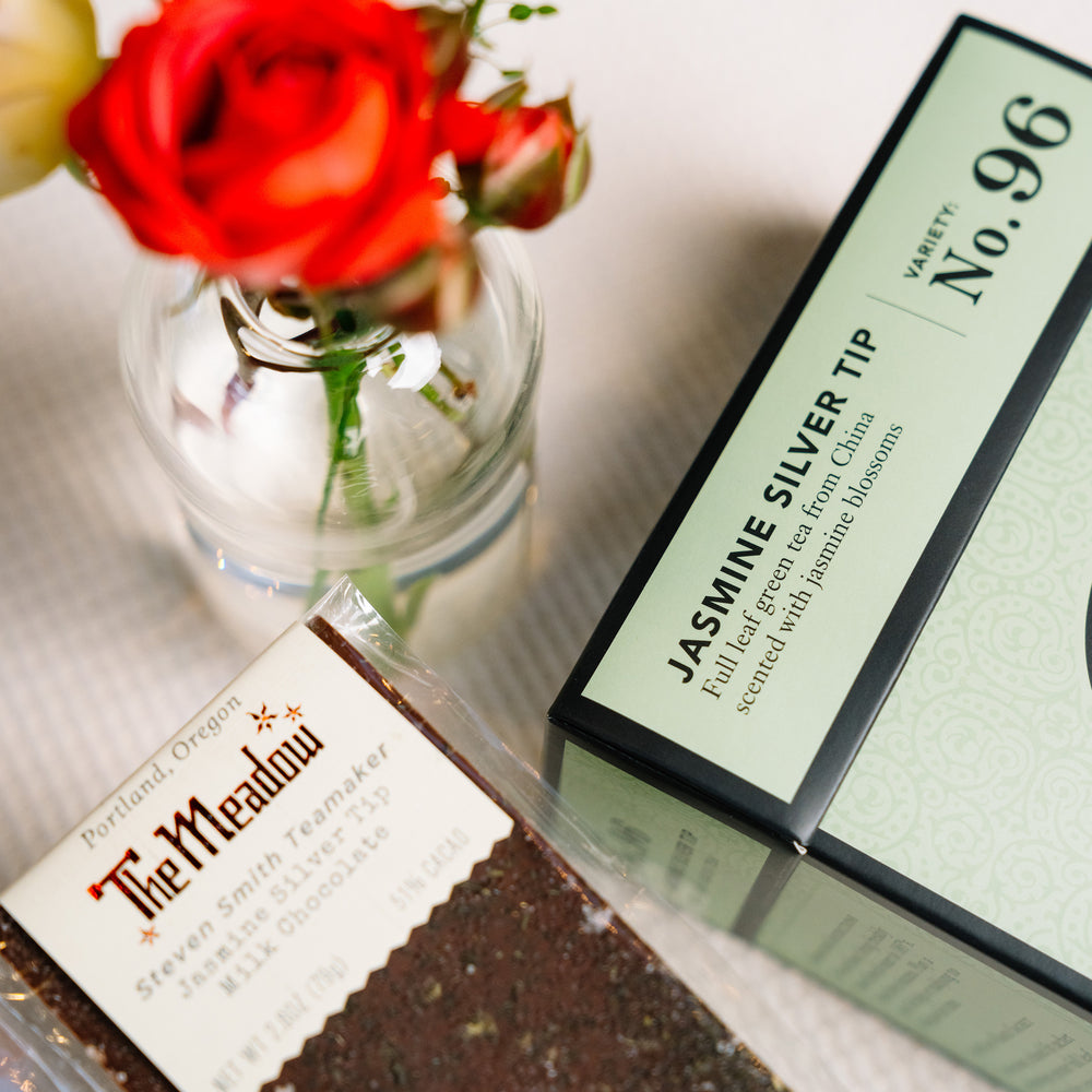 Close up view of the Meadow Jasmine Silver Tea chocolate bar beside box of Jasmine Silver Tea green tea.