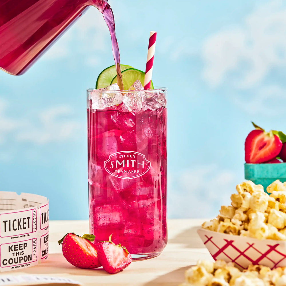 Glass of Lime Bramble Iced Tea on a picnic table garnished with lime.