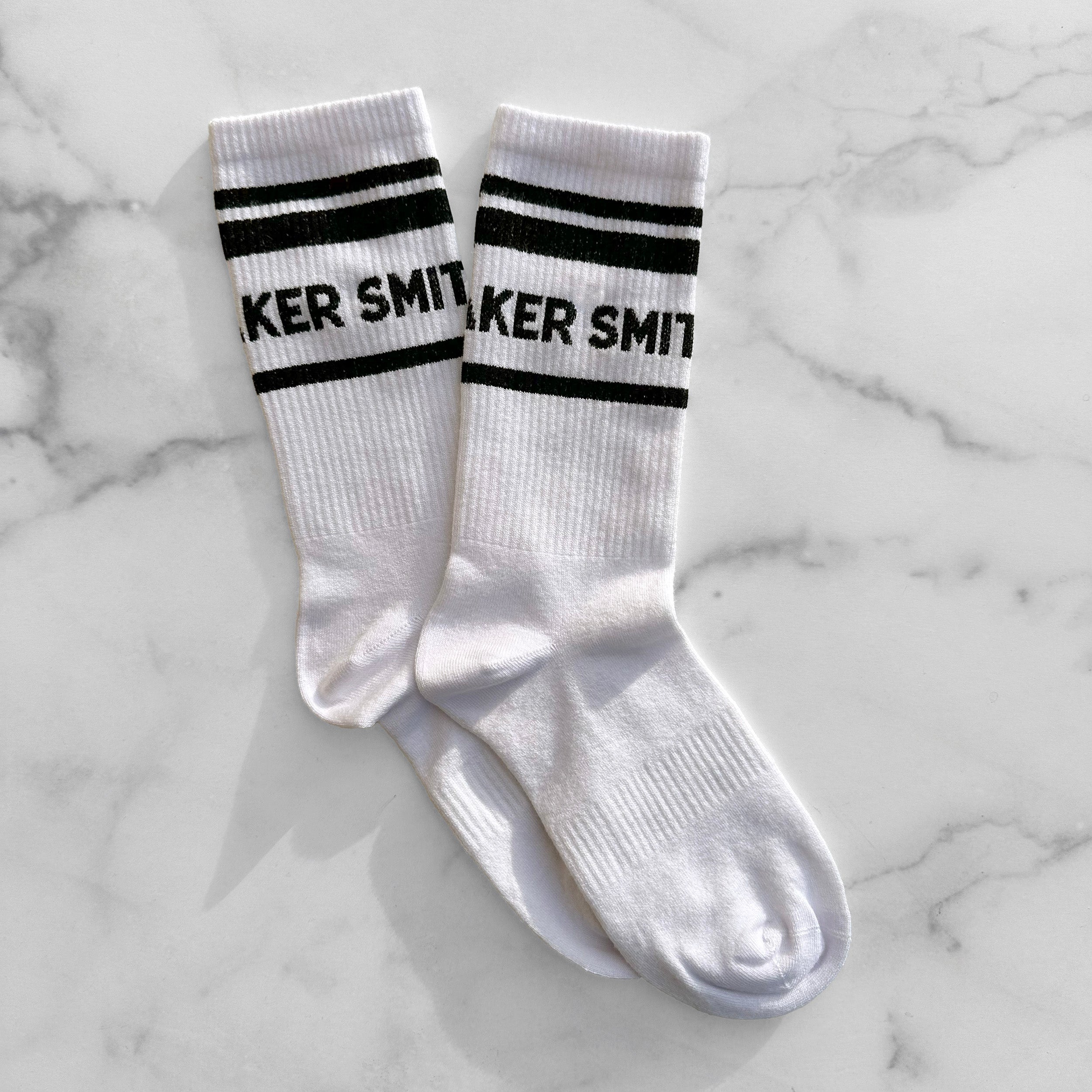 White crew socks with Smith Teamaker written around the ankle in black block letters against marble background.