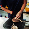 Teamaker in Yunnan, China wrapping Pu-erh cake into fabric in an industrial setting.