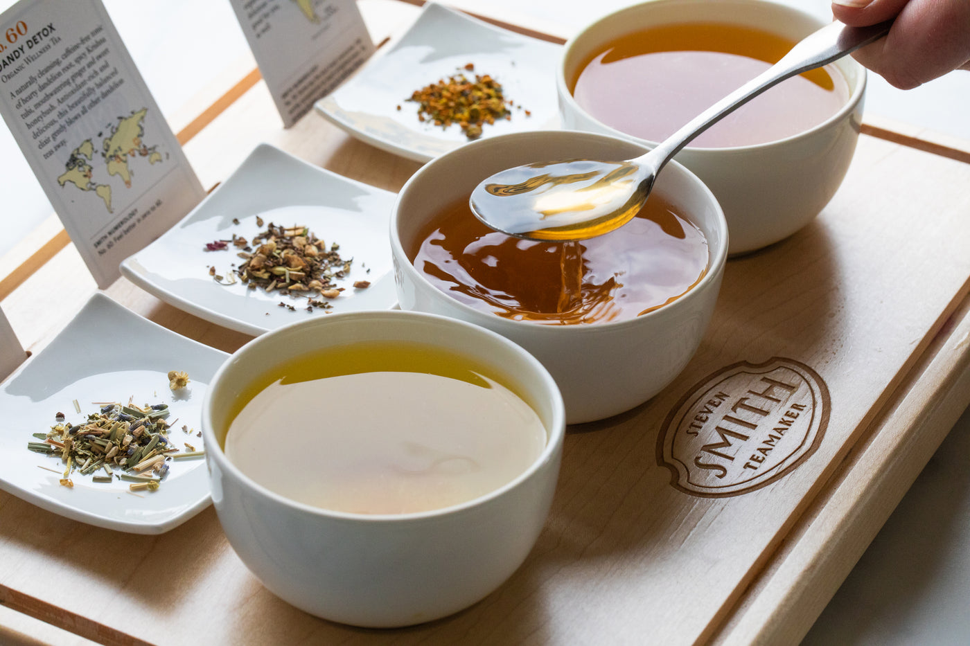 Flight of 3 teas with loose tea display on wooden board.